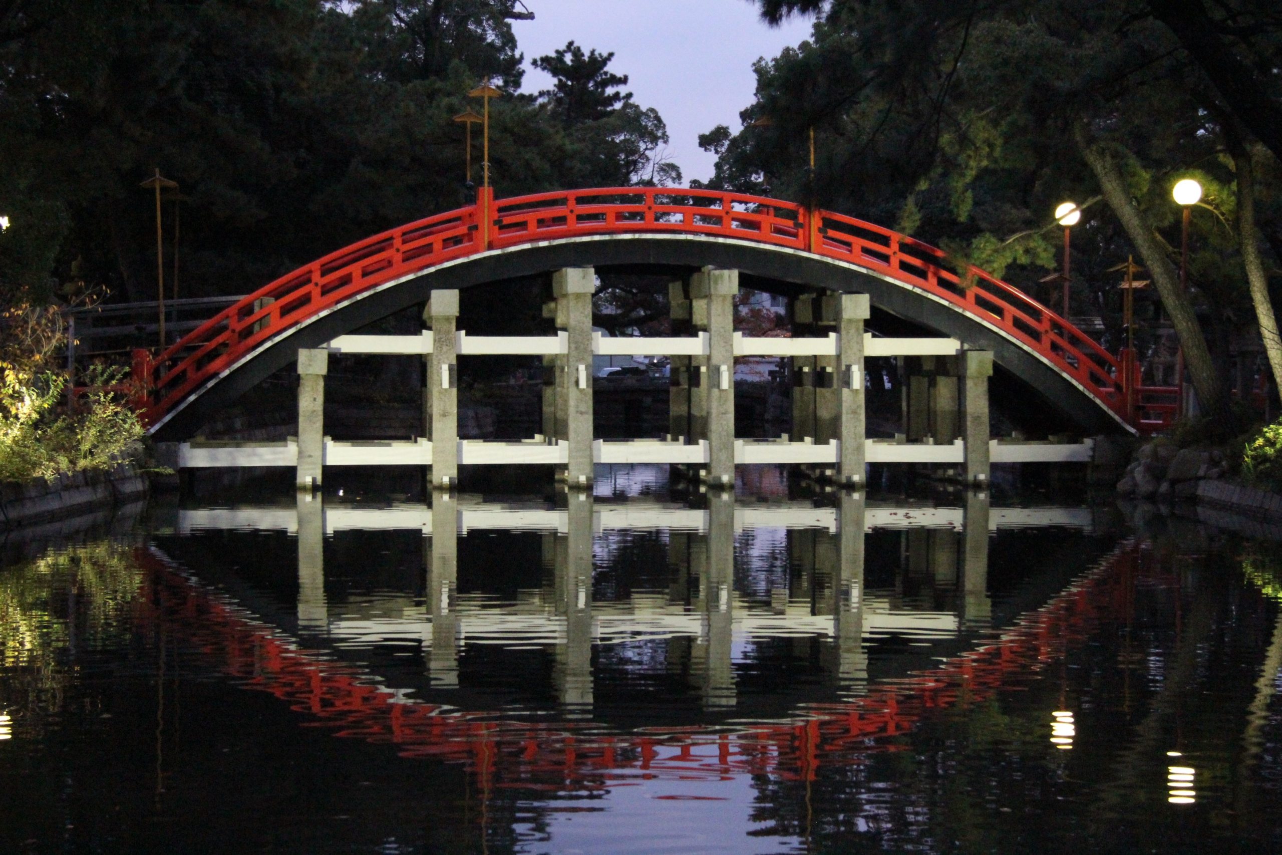 arched japanese bridge at night, with perfect reflection in water below, forming an oval