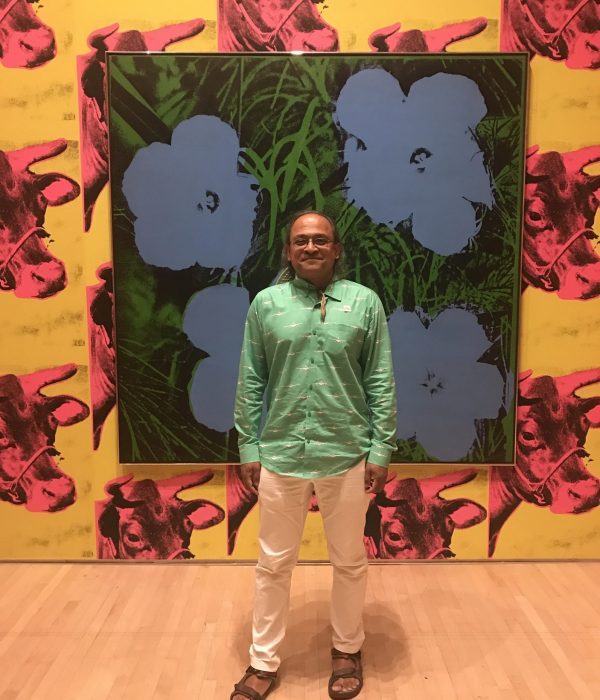 casual photo of ravi chandra, san francisco psychiatrist, posing in front of a warhol painting, smiling